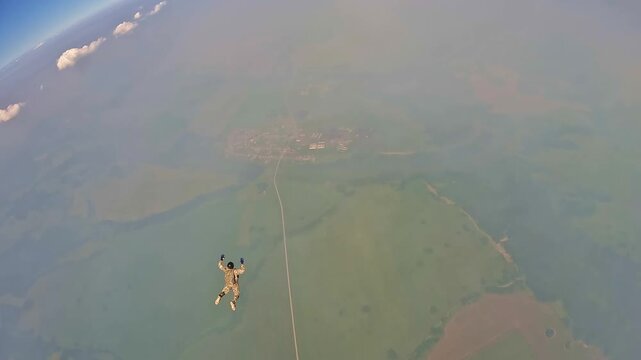 An athlete performs a jump from a great height, soaring above the clouds in free fall. Panoramic view from the action camera of extreme sports.

