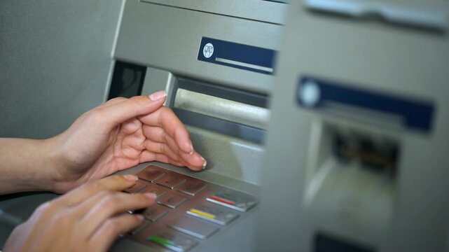 Lady hiding keyboard of automated teller machine with hand while inserting her pin code for privacy and safety in 4K Ultra HD footage
