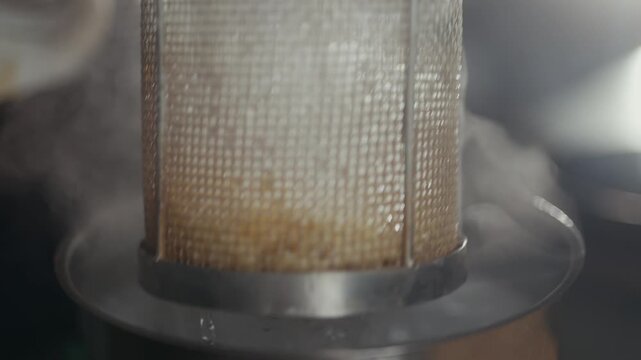 Honey dripping from honeycomb inside a wire mesh strainer closeup
