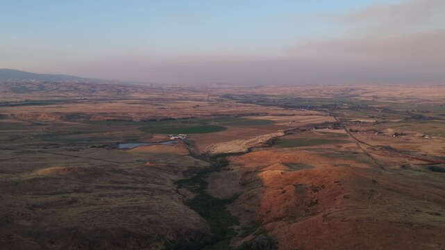 Aerial of Midvale Idaho high desert valley in Washington County with wildfire smoke and rolling hills and dry grassland at sunset