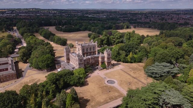 Grand Elizabethan hall mansion with courtyard surrounded by green trees
