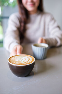 Vertical closeup image of a woman holding and serving two cups of hot coffee