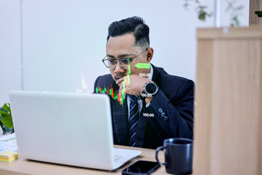 Senior Executive Using Laptop To Track Investment Candlestick Hologram At Workspace