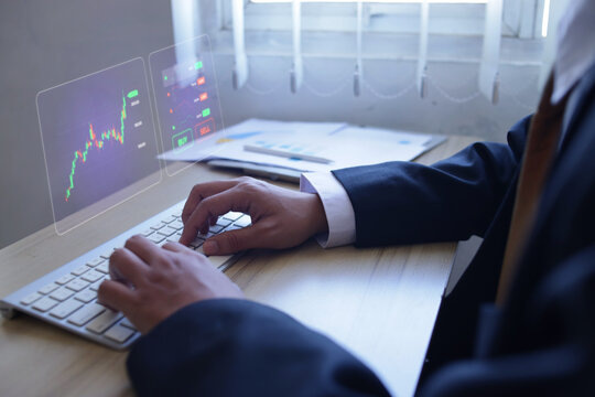 Closeup Man Typing on Keyboard with Digital Investments Hologram at Office Desk