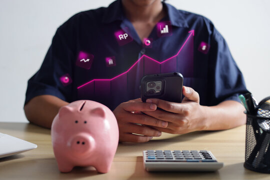 Close Up Of Investor Tracking Mobile Phone Financial Hologram Beside Piggy Bank