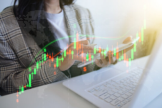 Businesswoman Analyzing Global Financial Trends Hologram On Tablet Beside Laptop At Workspace Desk