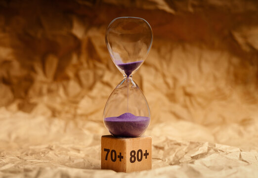 Hourglass with senior age blocks on crumpled pape,aging society, retirement and passing lifetime
