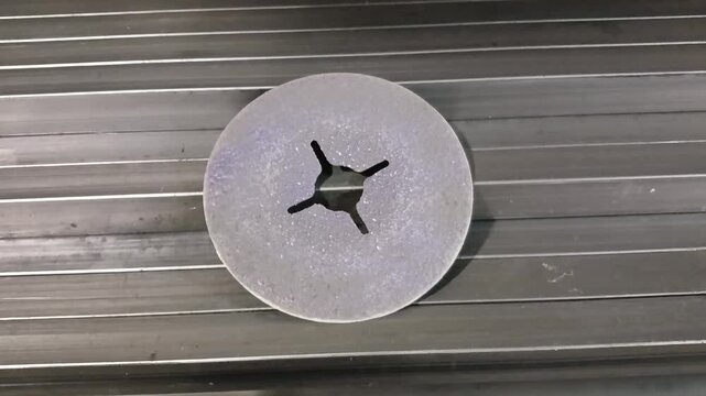 A grinding wheel used for metal processing lies on the metal