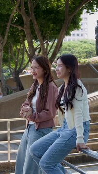 Two Happy Asian Students Talking and Laughing on University Campus
