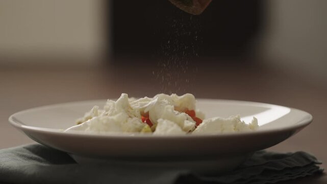 Slow motion making pesto penne pasta with mozzarella and tomatoes in deep plate closeup