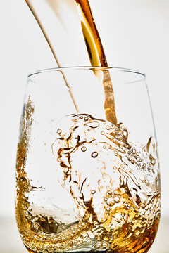 Amber Beverage Pouring Into Clear Glass with Bubbles