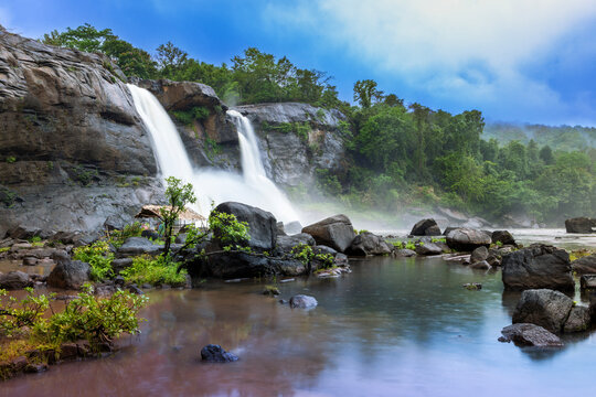 Gorgeous landscape, with Athirappilly Waterfall and foggy forest on background.