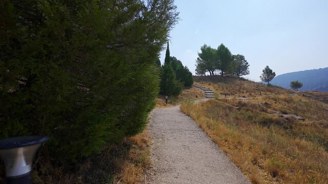 Gravel footpath and steps crossing a dry pine covered viewpoint above Cuenca in summer