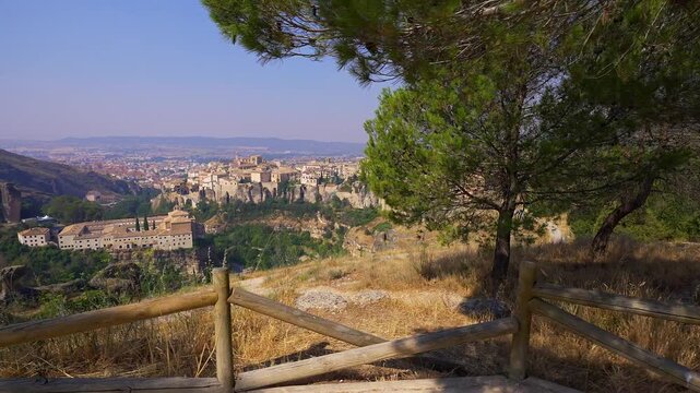Panoramic viewpoint toward Cuenca old town and Parador framed by pine trees and wooden fence