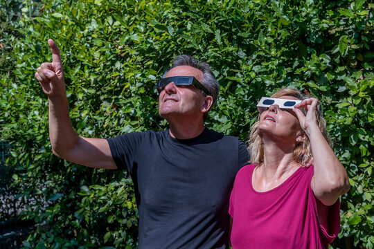 A couple of adults wears protective glasses to observe the sun and its upcoming eclipse