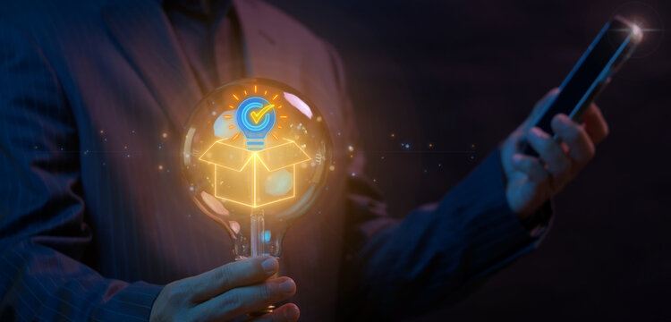 Shot of hand holding glowing lightbulb containing cargo package box and verified lightbulb checkmark icon. Dark neon lighting, verified cargo packaging idea and quality approved logistics concept.