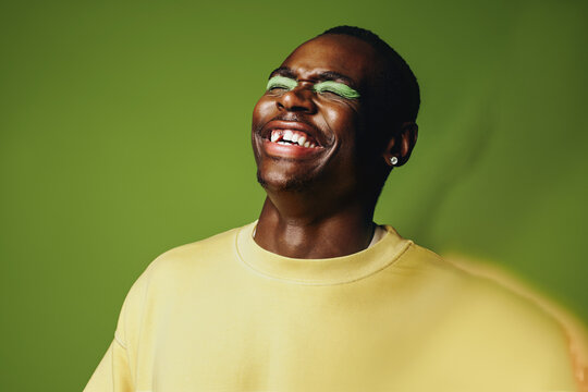 Man portrait laughing in studio with bold makeup and expressive style