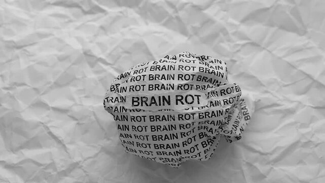 Crumpled paper ball with words Brain Rot on a crumpled white paper background.