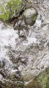 Top down vertical view of mountain stream flowing through wet stones.
