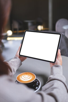 Vertical mockup image of a woman holding digital tablet with blank white desktop screen in cafe