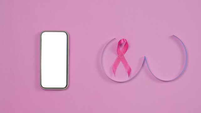 Breast cancer awareness concept with blank smartphone mockup and pink ribbon on pink background
