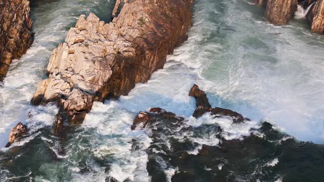 Early morning drone footage tracking left to reveal the broad cascade of Dhuandhar Waterfall on the Narmada River at Bhedaghat, Jabalpur, Madhya Pradesh, India.