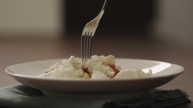 Slow motion making pesto penne pasta with mozzarella and tomatoes in deep plate closeup