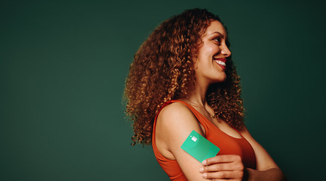Ready to tap and go, young woman man holds her credit card in a studio