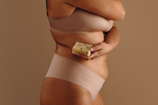 Woman holding unbranded wellness soap against neutral background