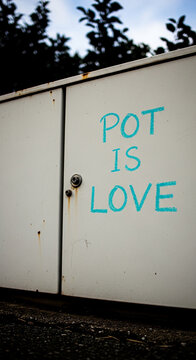 White metal box with "POT IS LOVE" written in turquoise crayon, symbolizing a message of peace and unity