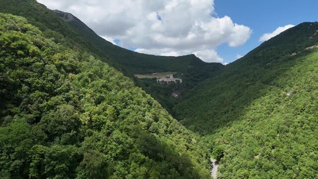 Ampio paesaggio montano ricoperto da foresta verde con pendii ripidi, vegetazione fitta e pareti rocciose esposte
