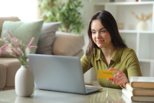 Teenage girl in green paying online using credit card and laptop