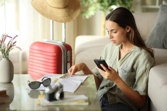 Tourist checking paper guide and phone on vacation
