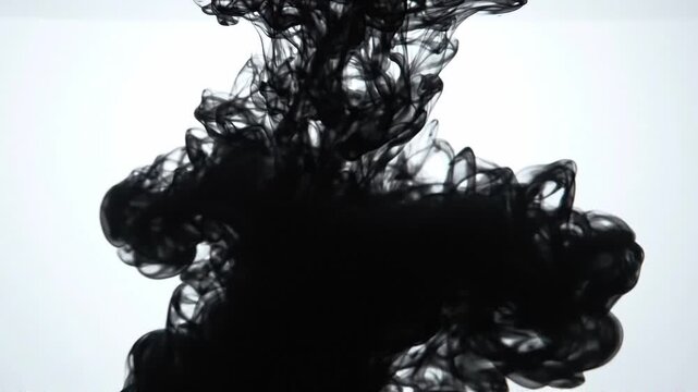 Black ink swirling and dispersing in water, creating dynamic shapes and patterns against a bright white background, showcasing fluid motion and transformation