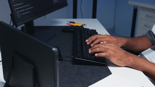 Close-up of Male Computer Programmer hand typing on keyboard while working on coding task at desk in tech office at night. Writing code, developing application, Ai machine learning LLM Concept.