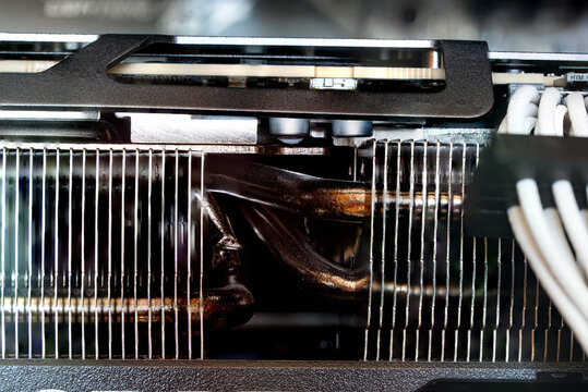 Macro shot of graphics card cooling heatsink fins, copper heat pipes, and white braided power cables inside desktop PC