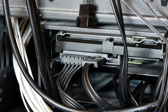 Close up of a 3.5 inch hard disk drive with connected SATA power and data cables inside a computer case drive cage