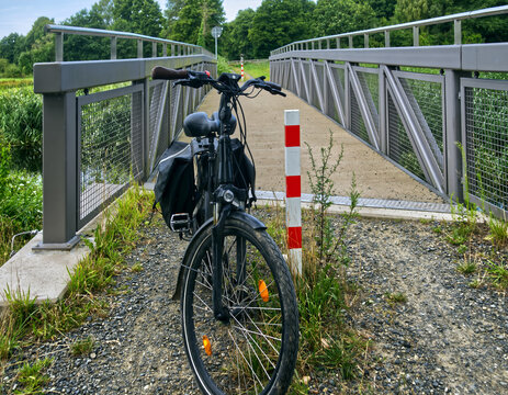 E bike resting on a gravel path, ready for a cycling tour across a modern bridge in germany's countryside