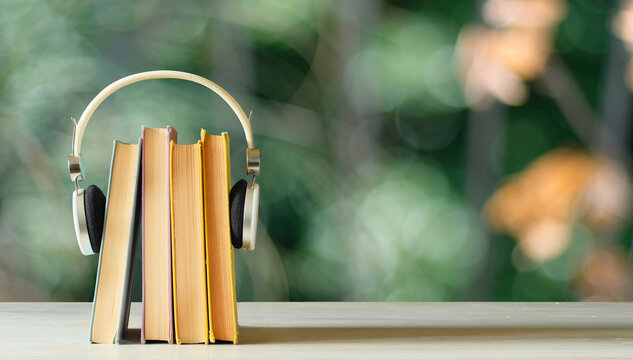 audiobooks concept with stack of books and headphones on blurred nature background,free copy space