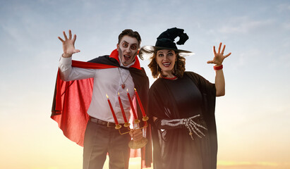 Obraz premium Happy Couple in Halloween Costumes Celebrating Outdoors at Sunset
