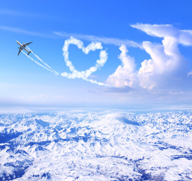 Airplane drawing heart in sky over the mountains. Jet flight route of aircraft in shape of heart. Heart-shaped flight path drawn by plane. Topic of holiday, travel, trip abroad on vacation, tour