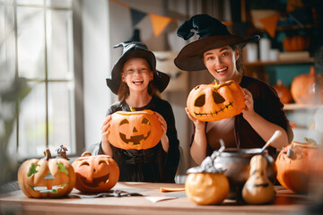 Obraz premium Joyful Mother and Daughter in Witch Costumes Carving Jack-o-Lantern