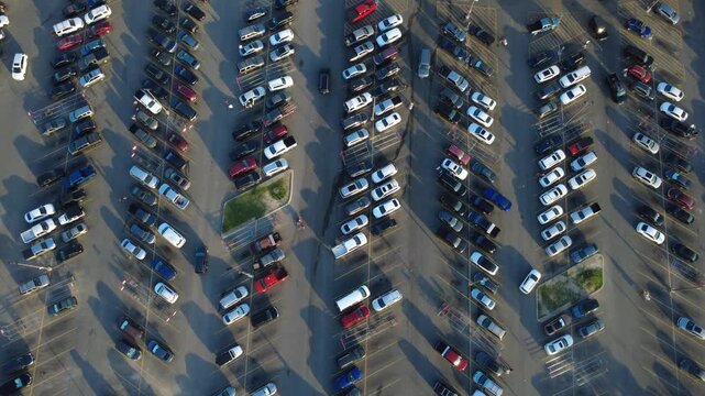 Orderly traffic lanes separate rows of parked cars in Alamo City commercial hub along Potranco Road at peak hours. Active shoppers maneuver past incoming vehicles, San Antonio, Texas