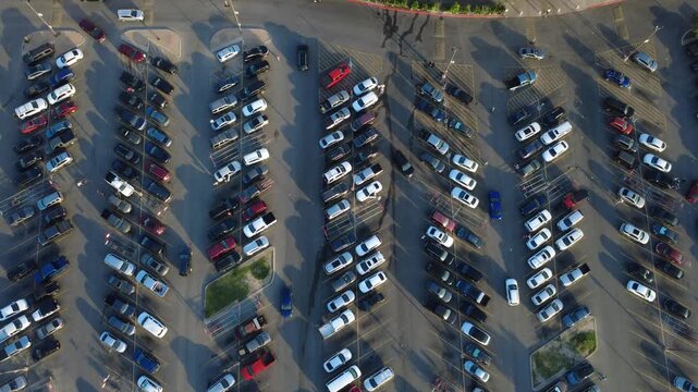 Elongated dark shadows stretch across marked parking stalls in Potranco Corridor retail area during prime shopping hours. Overflow vehicle volume fills supermarket lot, San Antonio, Texas