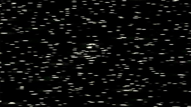 Sparkling silver glitter particles falling on dark background with glowing bokeh lights. Elegant abstract texture for luxury, festive, and cinematic visuals.