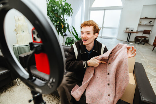 Fashion influencer records clothing video for ecommerce marketing at home studio setup.
