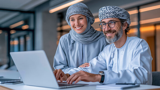 Smiling man and woman using laptop in modern office