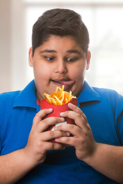 Young boy hungrily looking at fries (Obesity) 