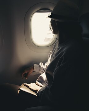 Close up silhouette of caucasian woman looks out the window of an flying airplane. Passenger on the plane resting beside the window