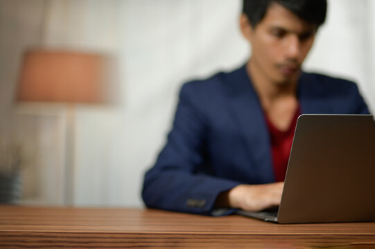 Young Man Using Laptop at Desk in Professional Indoor Office Setting